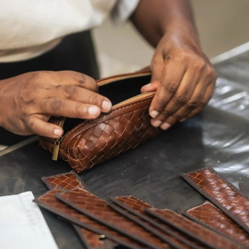 Person working on a brown leather wallet with visible stitching